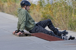 Boy with rollers relaxing on pavement